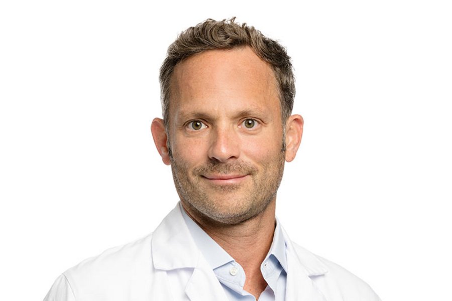 [Translate to English:] Profilfoto von David Bervini in weissem Arztkittel auf weissem Hintergrund