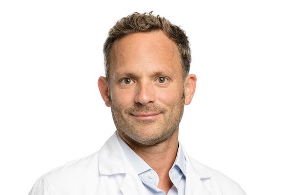 [Translate to English:] Profilfoto von David Bervini in weissem Arztkittel auf weissem Hintergrund